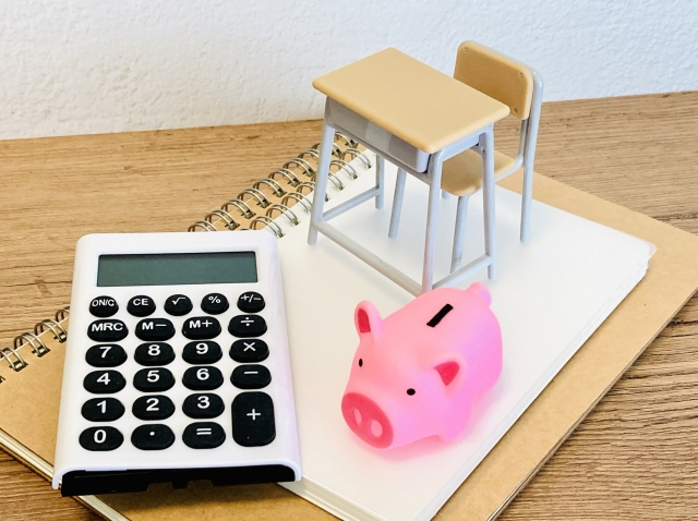 50代から金融の勉強を始めるイメージ。机の上の計算機と貯金箱